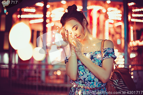 Image of Beautiful young woman smiling and talking garlands of lights at city
