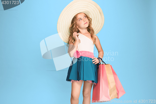 Image of The cute little caucasian brunette girl in dress holding shopping bags