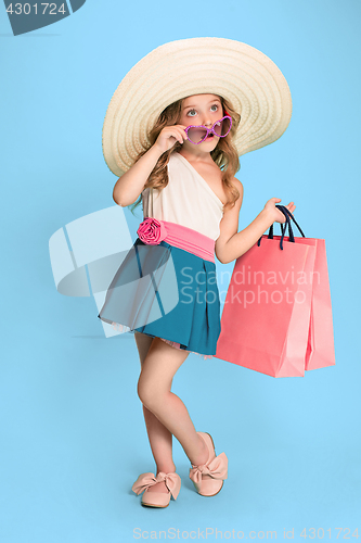 Image of The cute little caucasian brunette girl in dress holding shopping bags