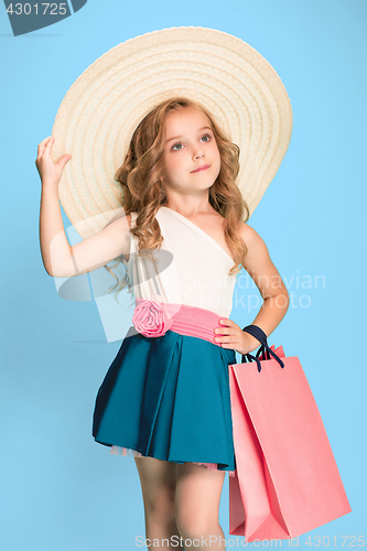 Image of The cute little caucasian brunette girl in dress holding shopping bags