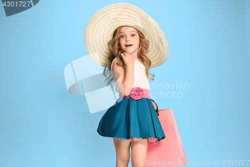 Image of The cute little caucasian brunette girl in dress holding shopping bags