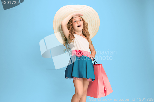 Image of The cute little caucasian brunette girl in dress holding shopping bags