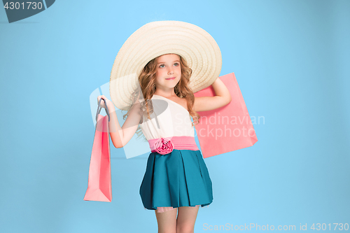 Image of The cute little caucasian brunette girl in dress holding shopping bags