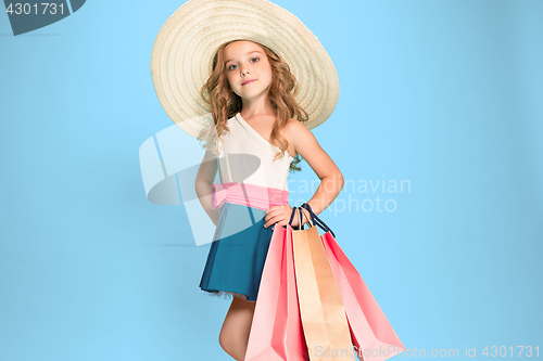 Image of The cute little caucasian brunette girl in dress holding shopping bags