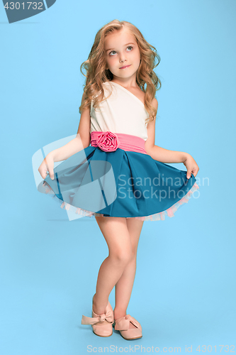Image of Full length of beautiful little girl in dress standing and posing over blue background