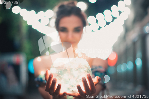 Image of Beautiful young woman smiling and talking garlands of lights at city