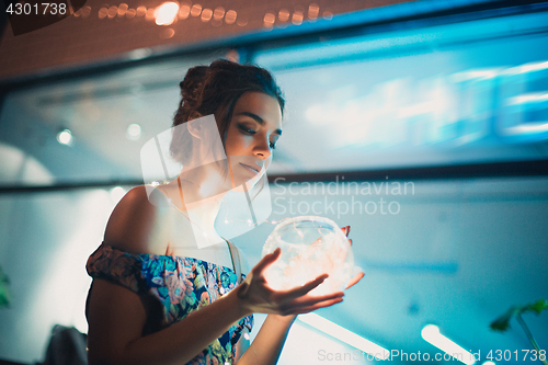 Image of Beautiful young woman smiling and talking garlands of lights at city