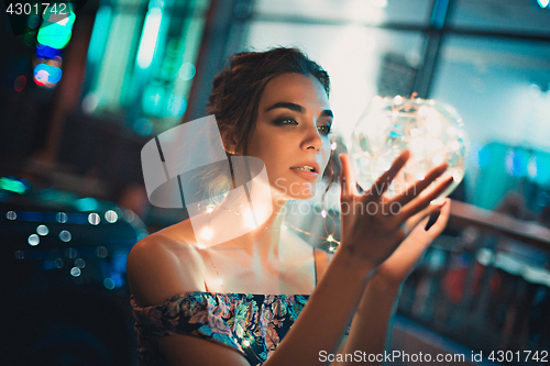 Image of Beautiful young woman smiling and talking garlands of lights at city