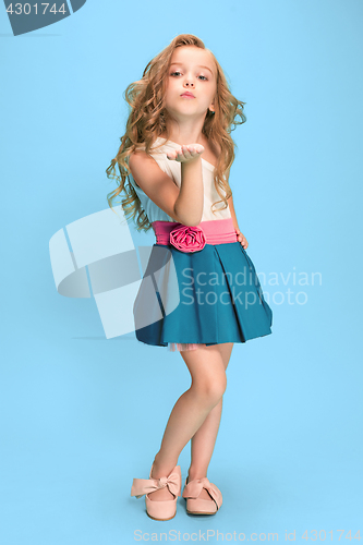 Image of Full length of beautiful little girl in dress standing and posing over blue background