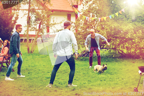 Image of happy friends playing with dog at summer garden