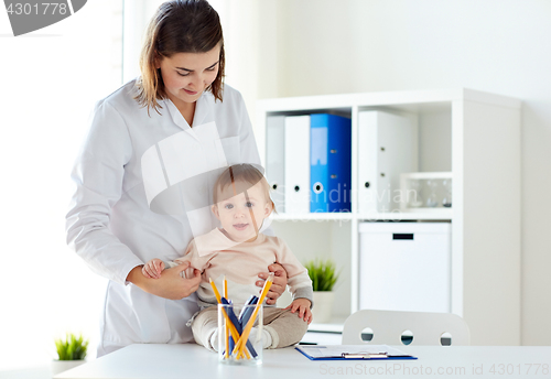 Image of happy doctor or pediatrician with baby at clinic