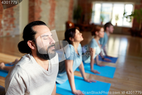 Image of group of people doing yoga cobra pose at studio
