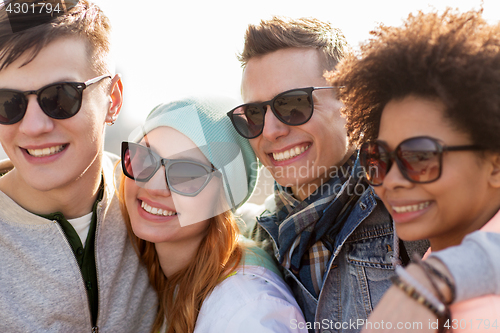Image of happy teenage friends in shades talking on street