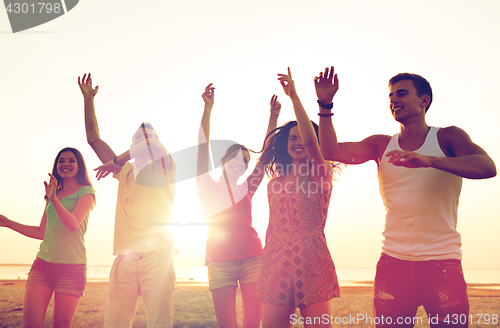 Image of smiling friends dancing on summer beach