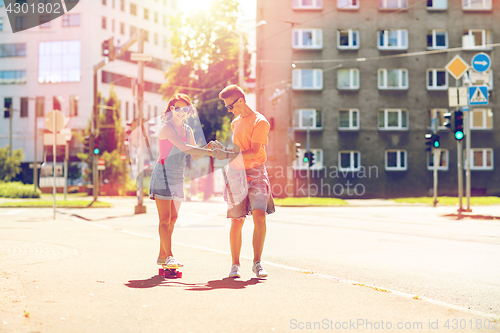 Image of teenage couple riding skateboards on city street