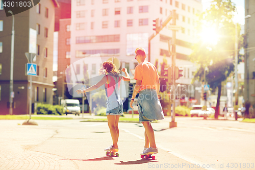 Image of teenage couple riding skateboards on city street