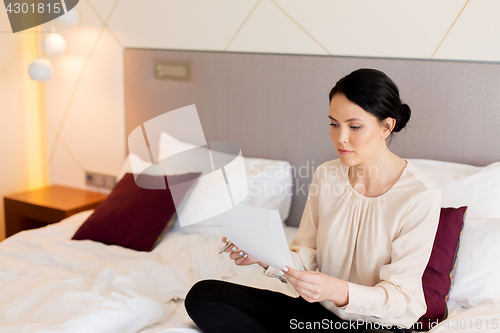 Image of businesswoman with papers working at hotel room