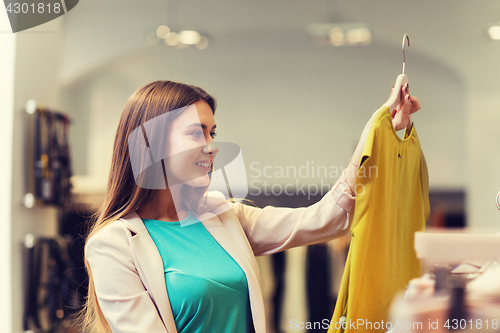 Image of happy young woman choosing clothes in mall