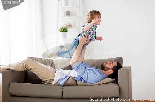 Image of happy young father playing with little son at home