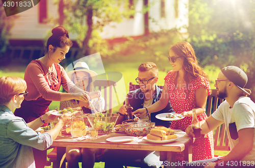 Image of happy friends having dinner at summer garden party