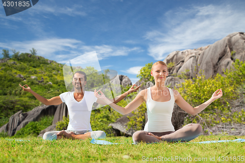 Image of happy couple doing yoga and meditating outdoors