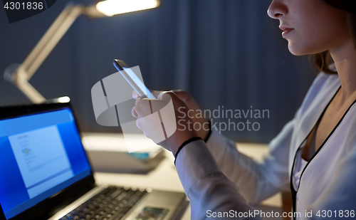 Image of businesswoman with smartphone at night office