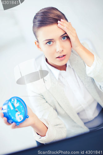 Image of stressed businesswoman holding clock