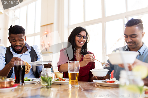 Image of happy friends eating at restaurant