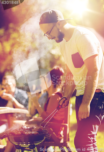 Image of man cooking meat on barbecue grill at summer party