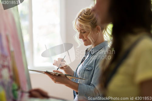 Image of woman artist with palette painting at art school