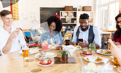 Image of happy friends with smartphones at restaurant