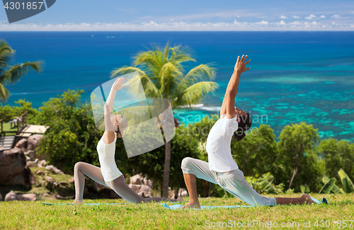 Image of couple making yoga in low lunge pose outdoors