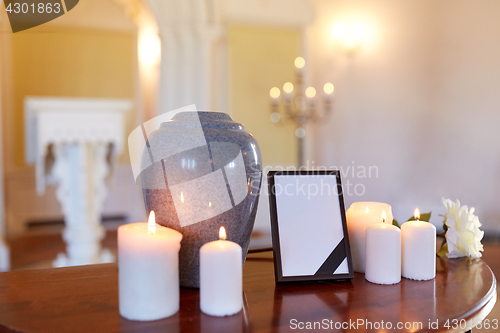 Image of photo frame, cremation urn and candles in church