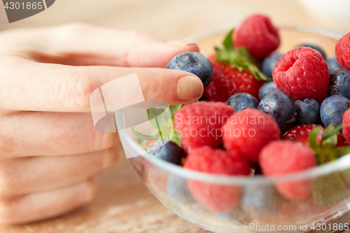 Image of close up of young woman hand with berries in bowl