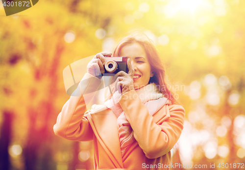 Image of woman photographing with camera in autumn park