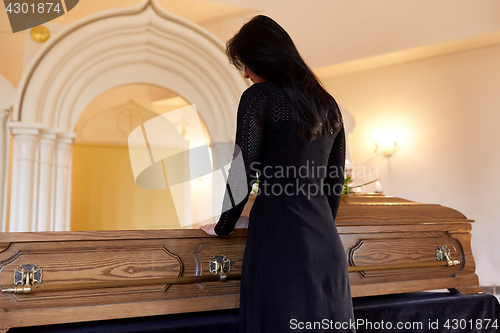 Image of sad woman with coffin at funeral in church