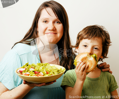 Image of mature woman holding salad and little cute boy with hamburger te