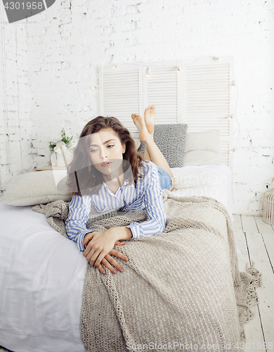 Image of young pretty brunette woman in her bedroom sitting at window, happy smiling lifestyle people concept 