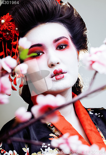 Image of young pretty geisha in kimono with sakura and red decoration design on white background