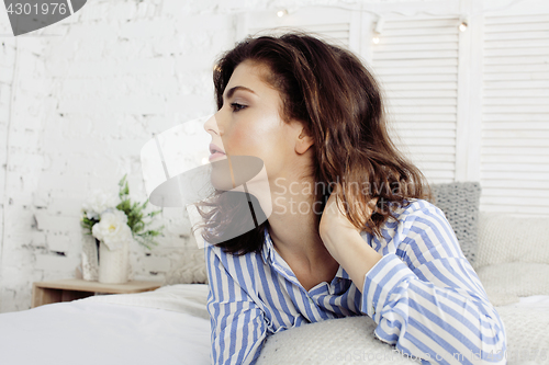 Image of young pretty brunette woman in her bedroom sitting at window, happy smiling lifestyle people concept 