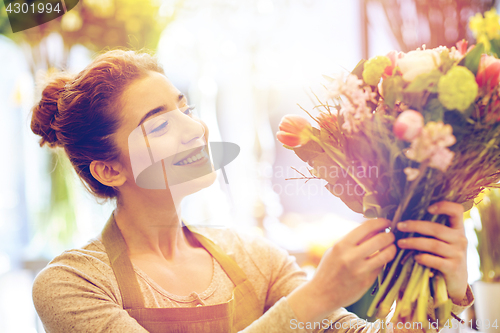 Image of smiling florist woman making bunch at flower shop