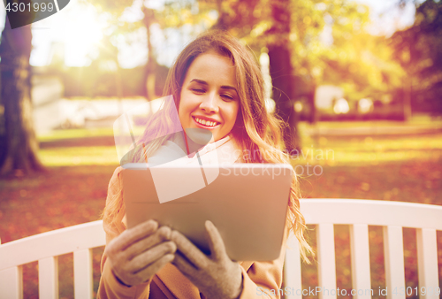 Image of happy young woman with tablet pc in autumn park