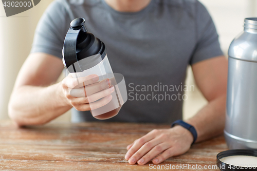 Image of close up of man with protein shake bottle and jar