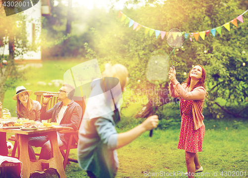 Image of happy friends playing badminton at summer garden