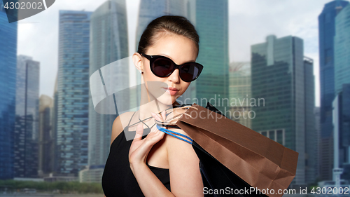 Image of happy woman in black sunglasses with shopping bags