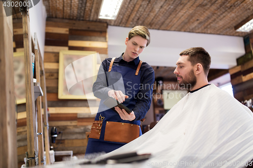 Image of barber showing tablet pc to man at barbershop