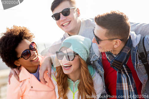 Image of happy teenage friends in shades laughing outdoors