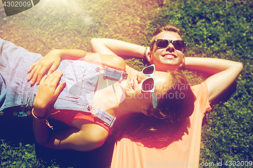 Image of happy teenage couple lying on grass at summer