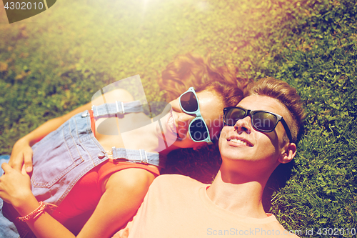 Image of happy teenage couple lying on grass at summer