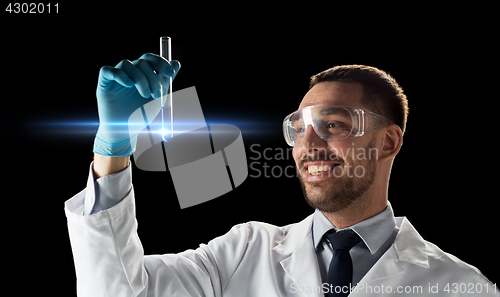 Image of smiling scientist in goggles with test tube